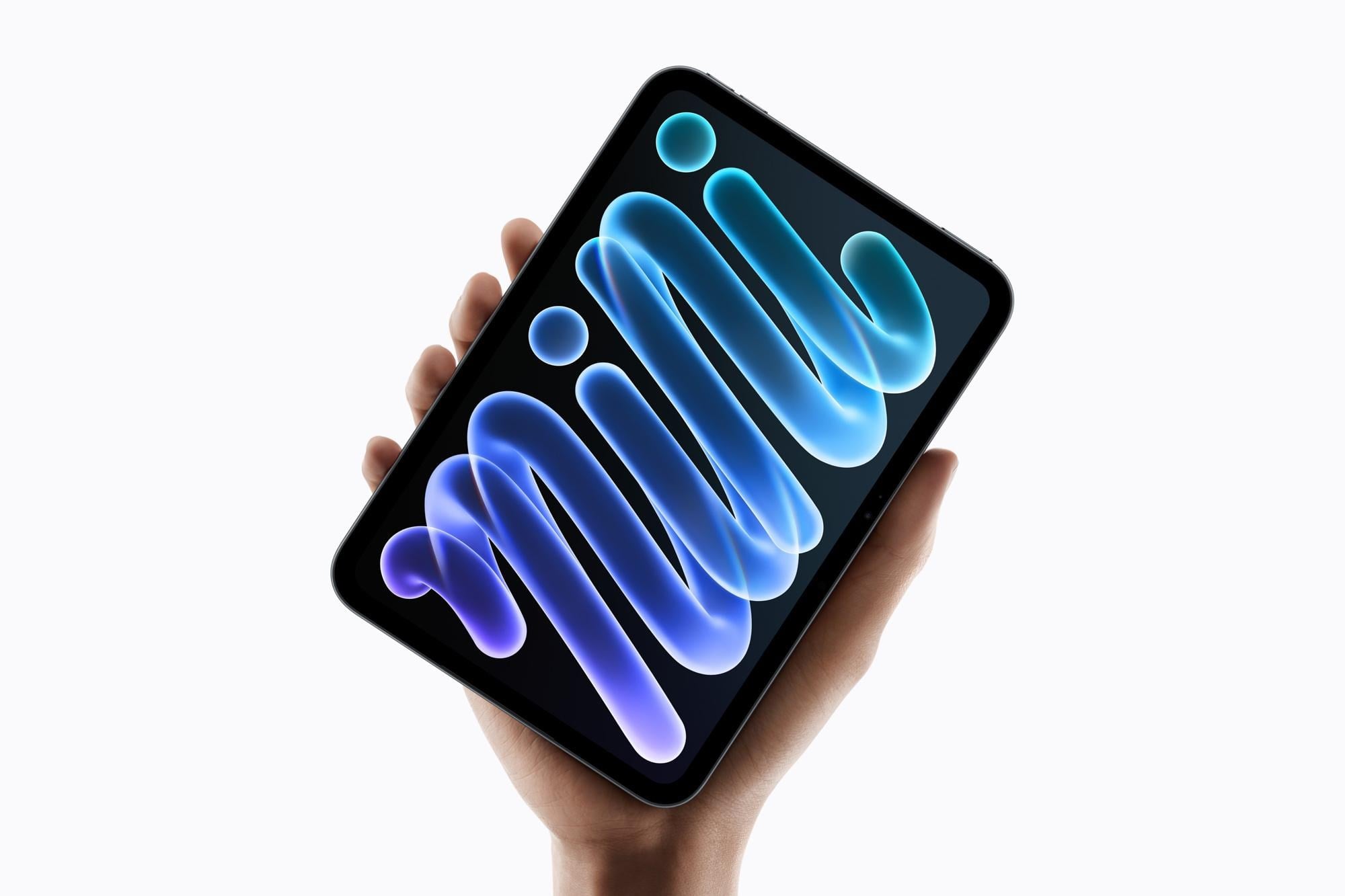Hand holding tablet device displaying abstract blue and teal glowing organic shapes on dark background