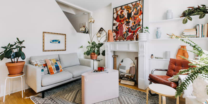 Same living room interior featuring couch, fireplace, plants, and geometric patterned rug from different angle