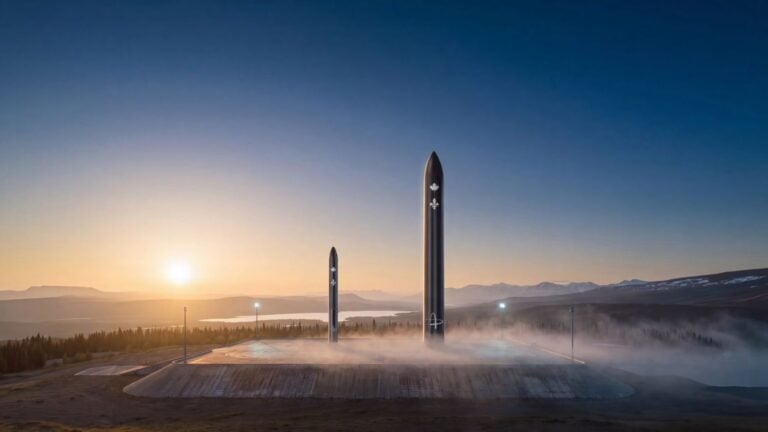 Two tall rocket structures emerging from mist at sunrise with mountains in background