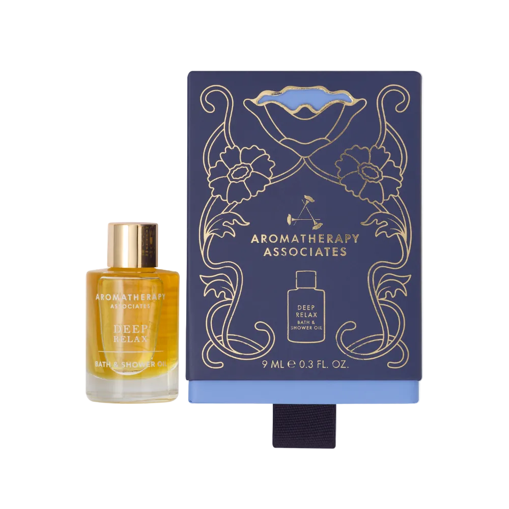 Deep Relax Bath & Shower Oil bottle next to navy gift box with gold floral design and black ribbon