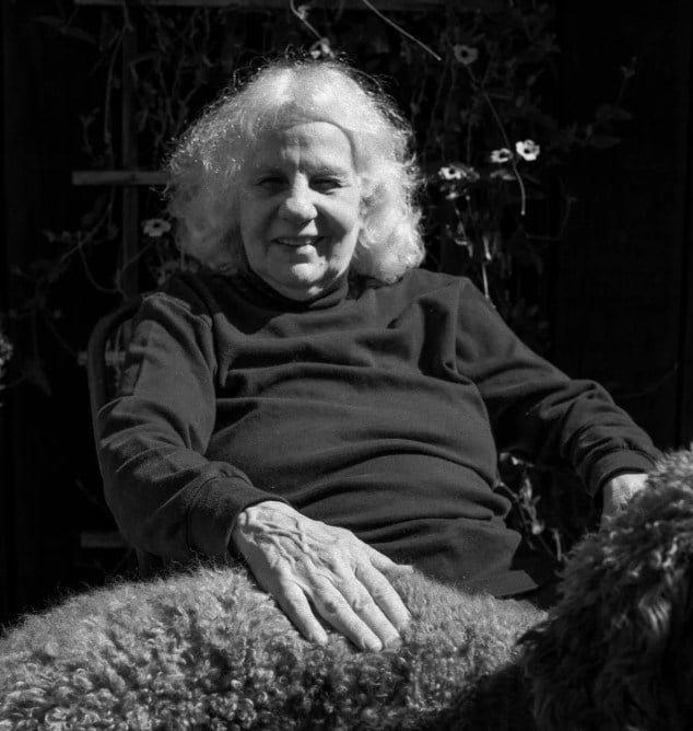 Black and white portrait of an elderly woman with white hair sitting outdoors