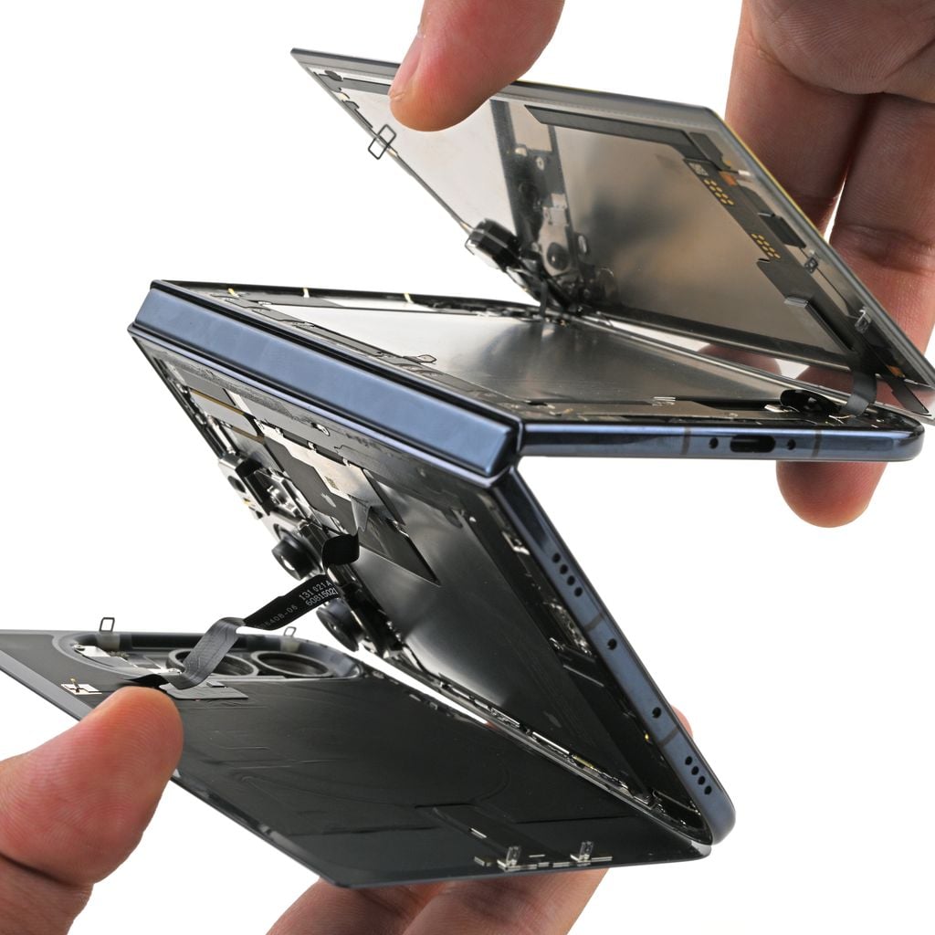 Hands holding disassembled smartphone showing separated display and internal components