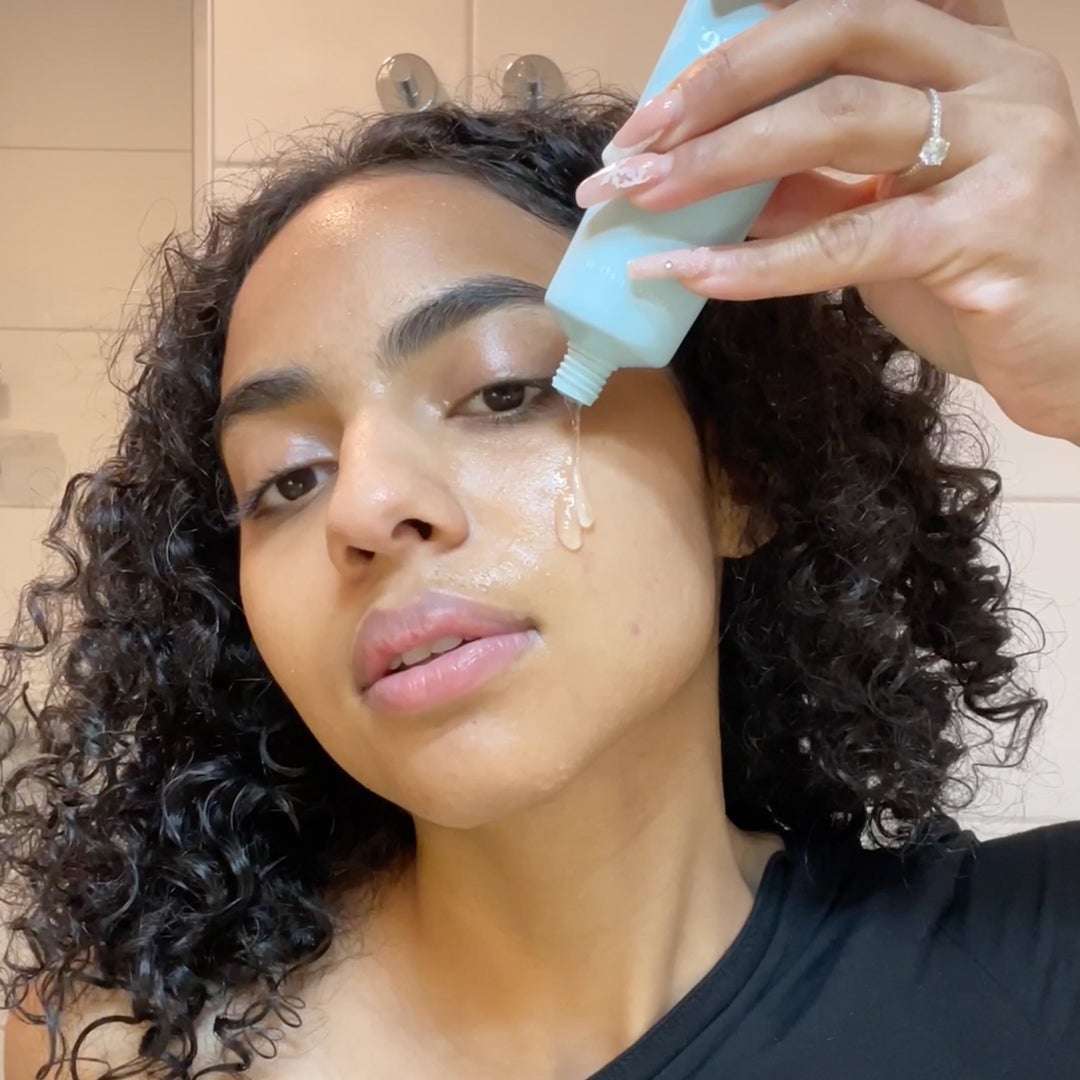 Person applying liquid facial serum to cheek with eye-area focus