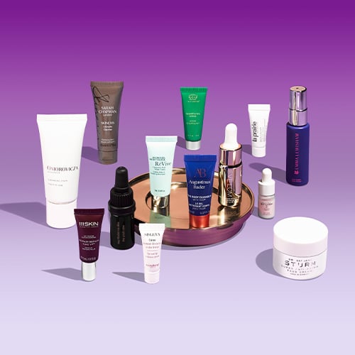 Collection of skincare and beauty products arranged on purple surface