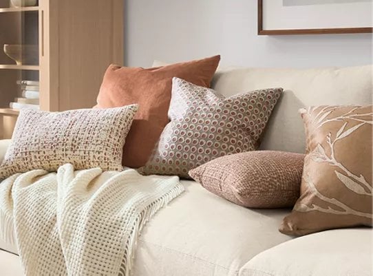 Beige sofa with decorative pillows in earth tones and textured patterns arranged together
