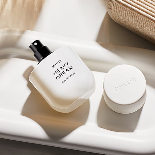 White spray bottle and jar of heavy cream product on white tray with woven placemats
